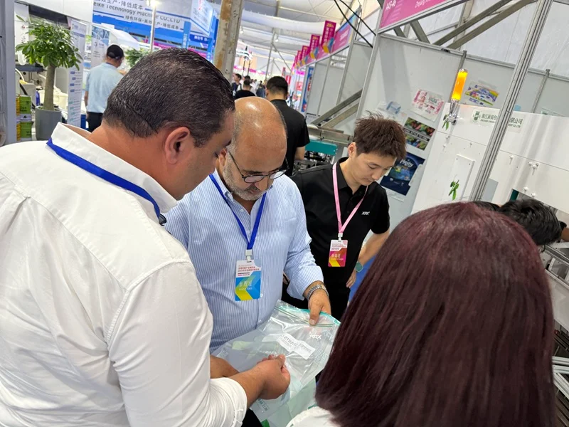 Longgang Printing Expo, clients checking product brochures at Booth A43-46 of Zhejiang Xinxin Packaging Machinery